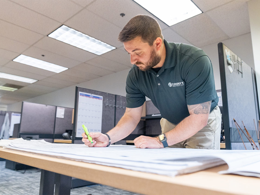 Construction professional reviewing building plans in office.