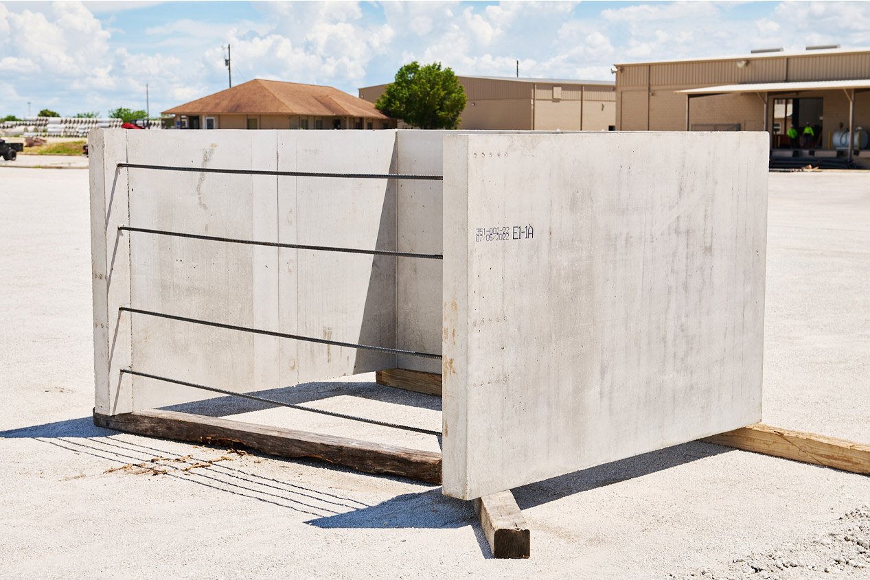 One segment of a precast elevator shaft sits on wooden blocks in a production yard.